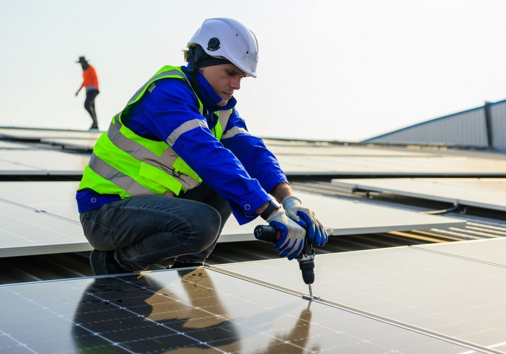 Professional technicians installing solar panels on rooftop of plant